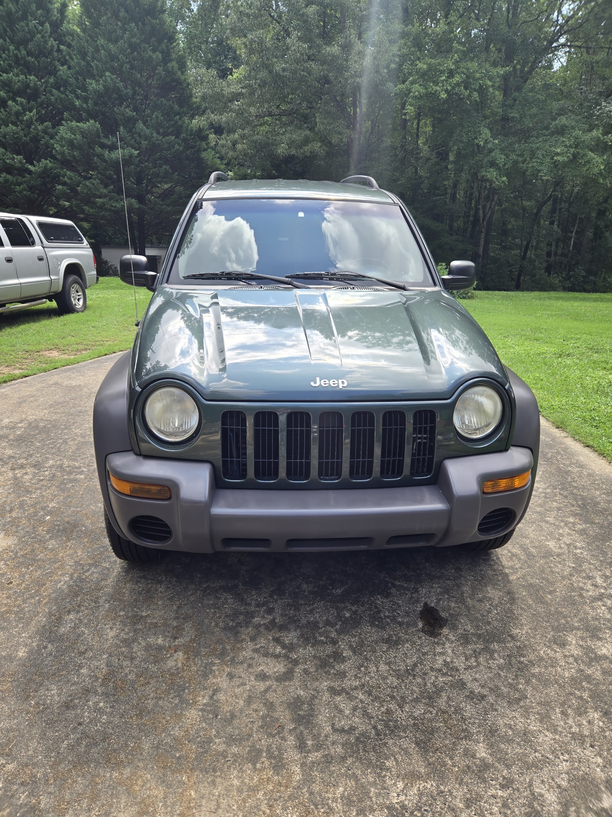 Green Jeep Liberty parked in a driveway after a wash
