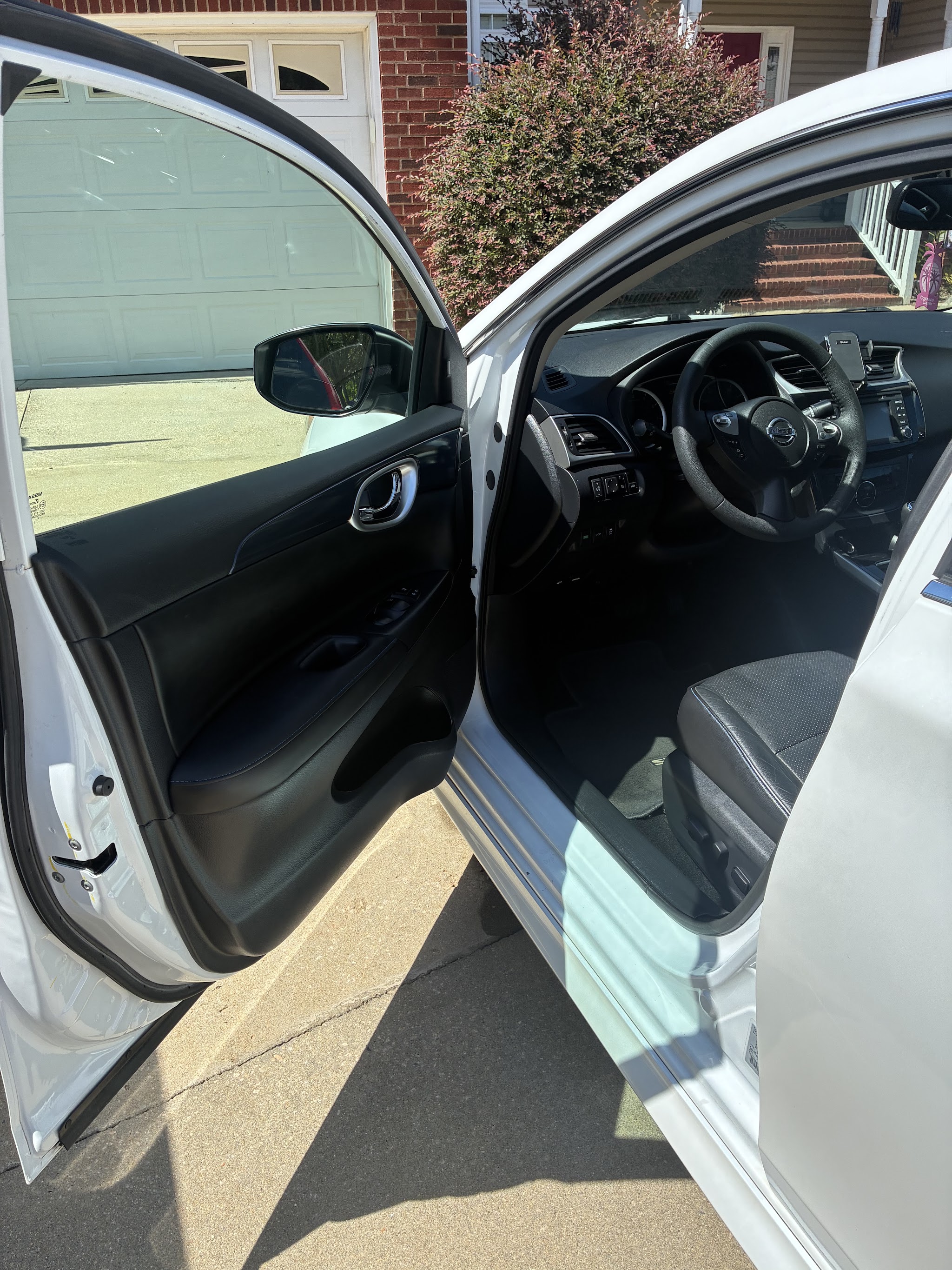 Open driver door showing a clean Nissan interior